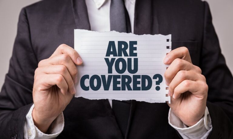 Man standing showing a piece of paper that says" are you covered".